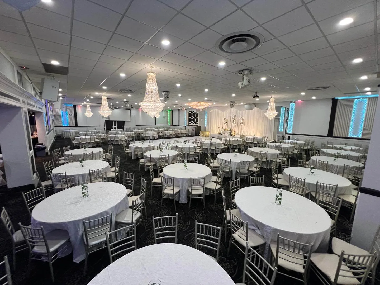 Round banquet tables in white linen with folded napkins at each place.