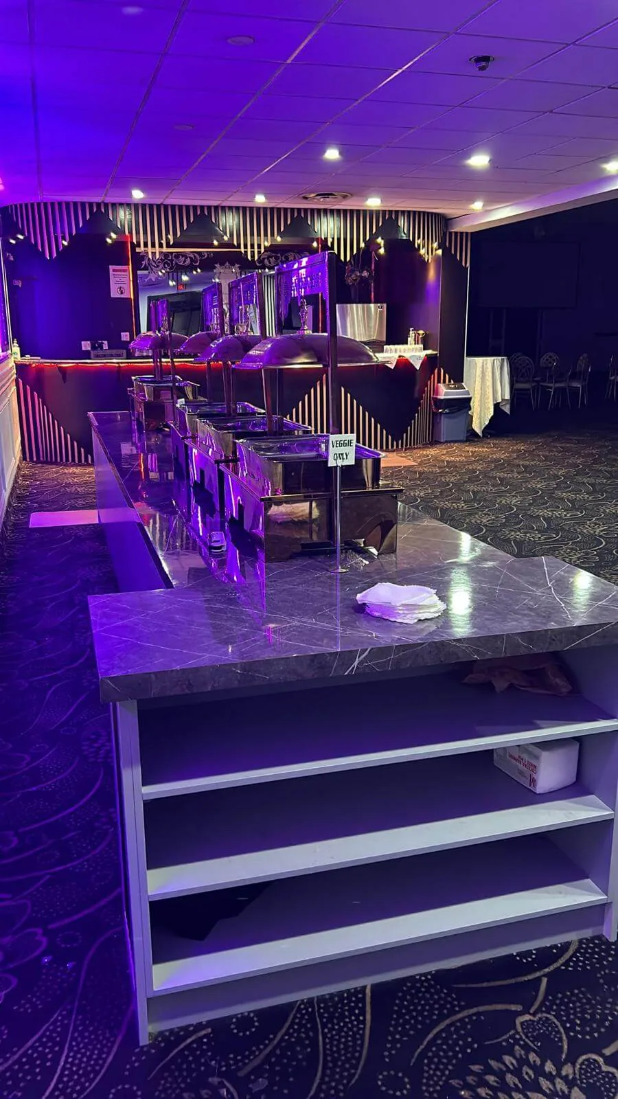Bar counter lit in purple, stocked and staffed for an event.