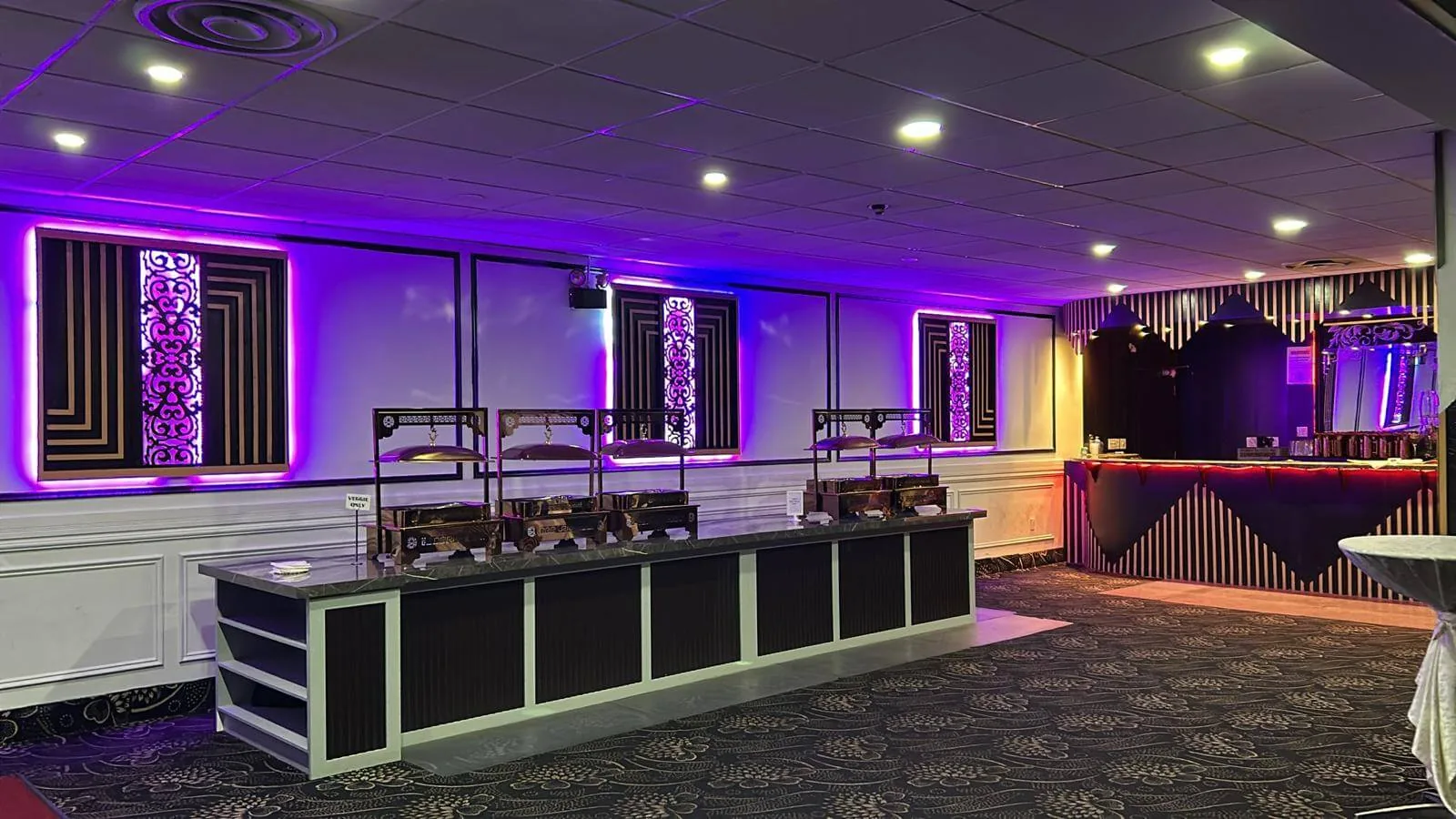 Bar lounge under purple lighting with seating for guests between courses.