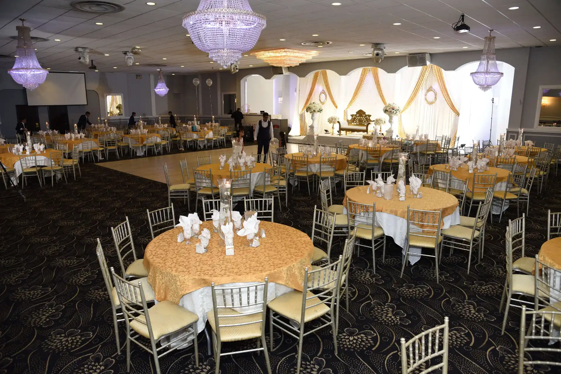 Gold-accented place settings and centrepieces on a banquet table.