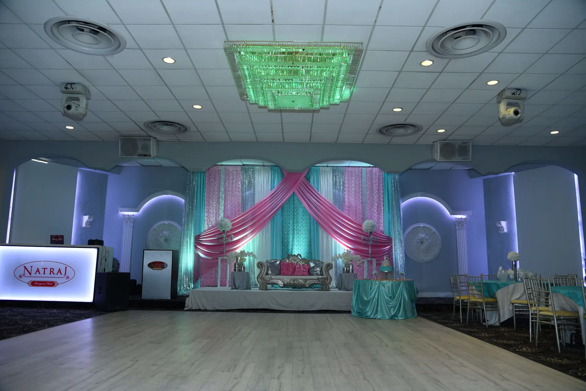 Stage set in teal and pink drapery with a decorated centre seat.